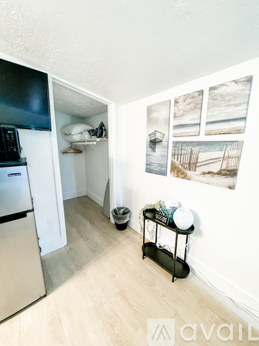 A kitchen with a fridge, a stove, a microwave, a fan and a table with a plant on it.