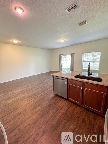 A kitchen with wooden floors and a counter with a sink.