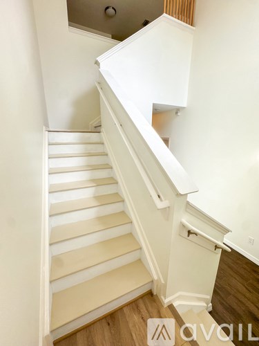 A white staircase with wooden steps and handrail.