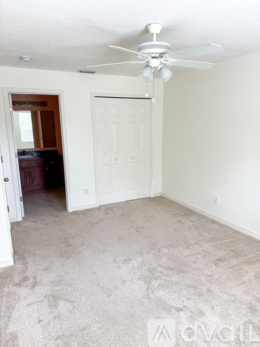 A room with a carpeted floor and a ceiling fan.
