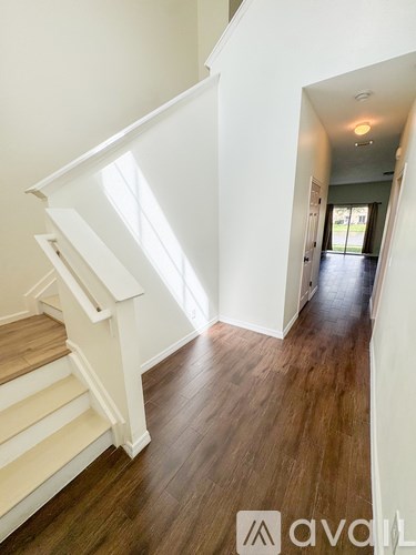 A hallway with wooden floors and white walls.