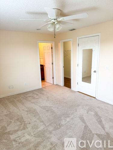 A room with a carpeted floor and a ceiling fan.