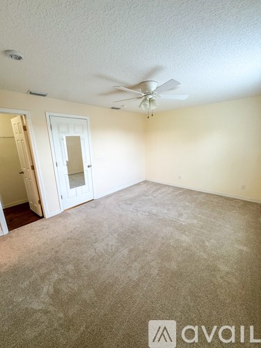 A room with a carpeted floor and a ceiling fan.
