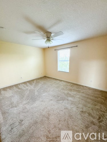 A room with a ceiling fan and a window with blinds.