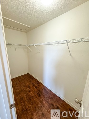 A white closet with a wooden floor and a white door.
