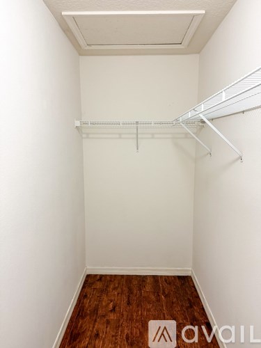 A white closet with a wooden floor and a white shelf.