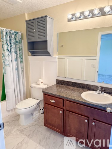 A bathroom with a toilet, sink, and cabinet.