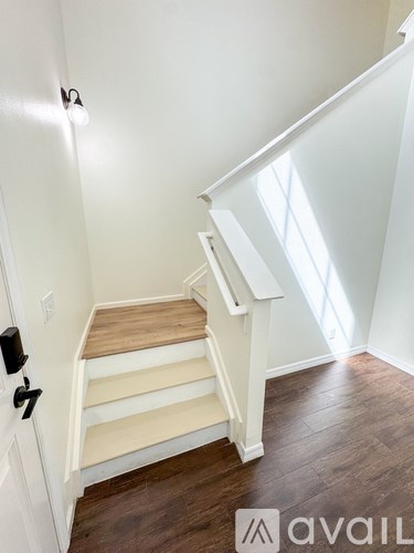 A white door with a black handle and a set of stairs leading to a landing with a skylight.