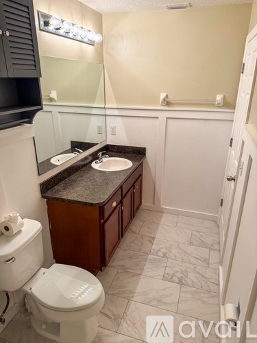 A bathroom with a toilet, sink, and cabinet.