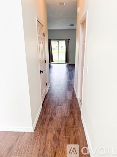 A long hallway with wood floors and white walls.