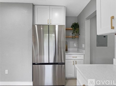 A kitchen with a stainless steel refrigerator and white cabinets.