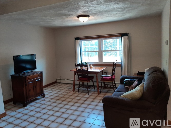 A living room with a television, a couch, and a dining table.