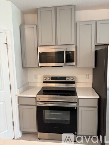 A kitchen with white cabinets and black appliances.