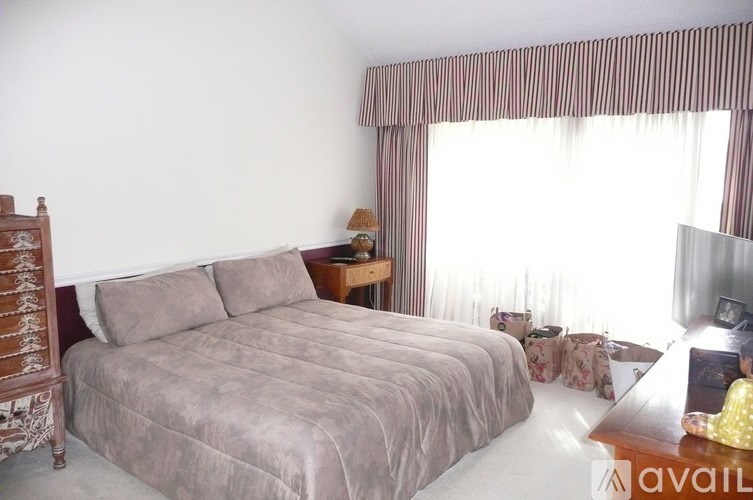 A bedroom with a large bed and a wooden nightstand.