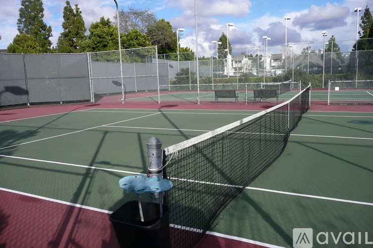 A tennis court with a net and a water bottle on the ground.