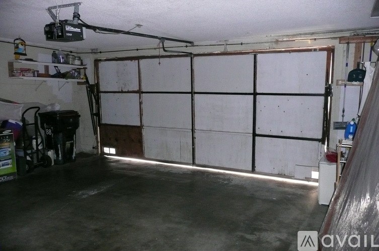 A garage with a white wall and a black shelf.