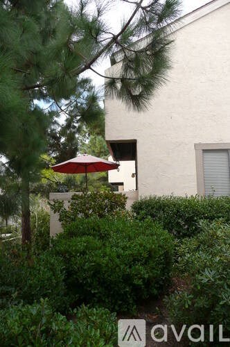 A red umbrella is in front of a white building.