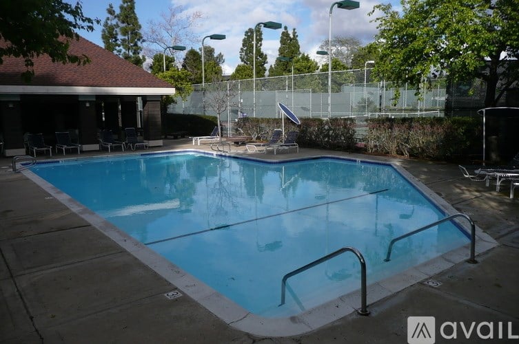 A large outdoor swimming pool with a diving board and a fence surrounding the area.