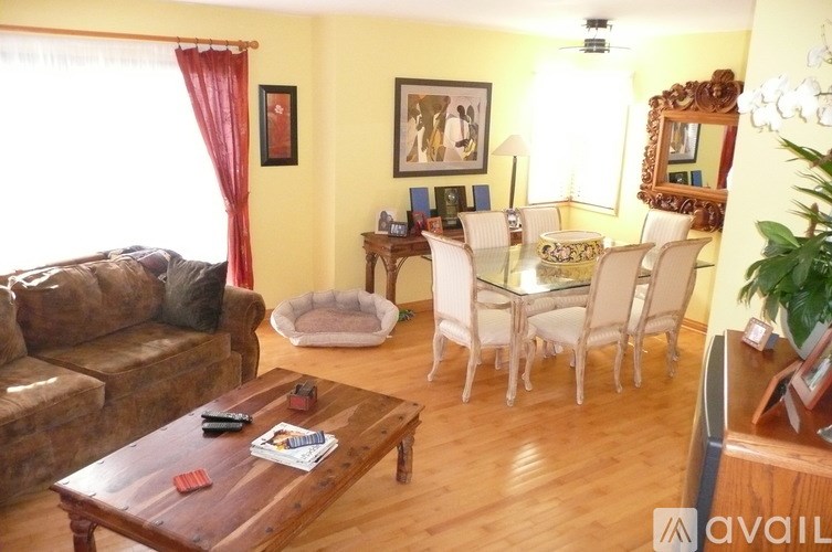 A living room with a brown couch, a coffee table, and a dining table with chairs.