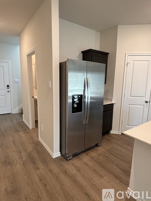 A kitchen with a stainless steel refrigerator and wooden flooring.