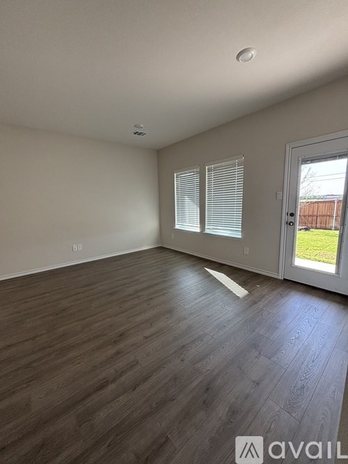 A room with wooden flooring and a door leading outside.