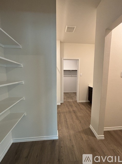 A hallway with a white door and shelves on the wall.