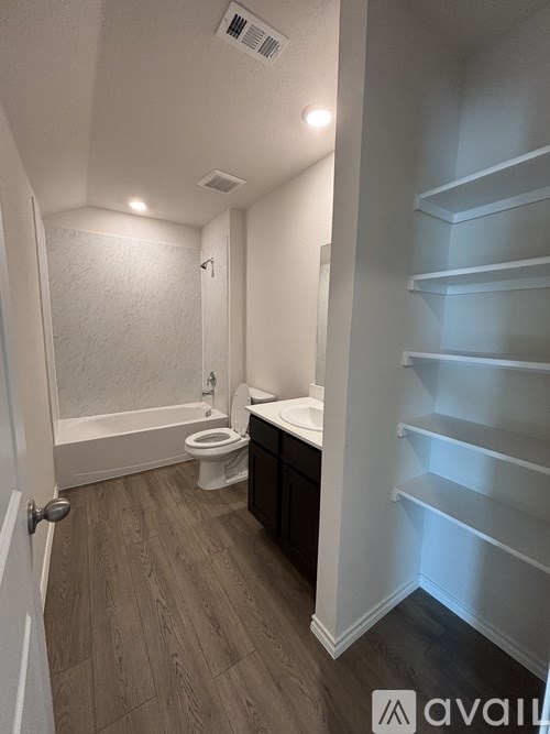 A bathroom with a toilet, sink, and shelves.