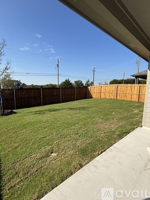 A backyard with a wooden fence and a grassy area.