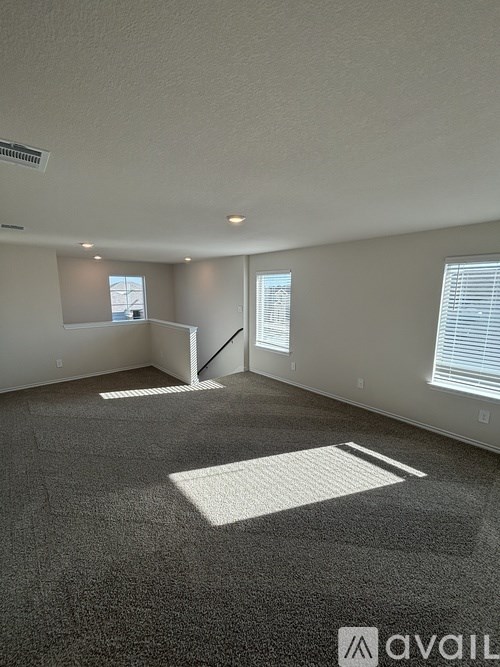 A spacious room with a carpeted floor and a window with blinds.