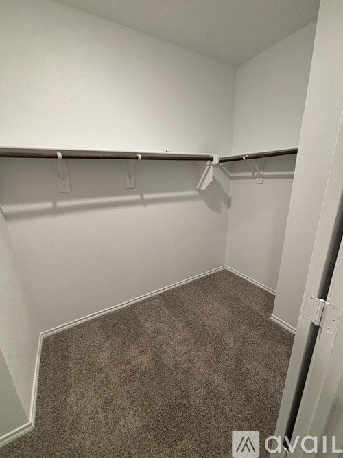 A small, empty room with a carpeted floor and a row of clothes hangers.