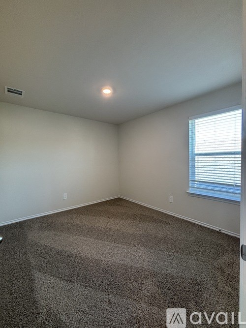 A carpeted room with a window and a door.
