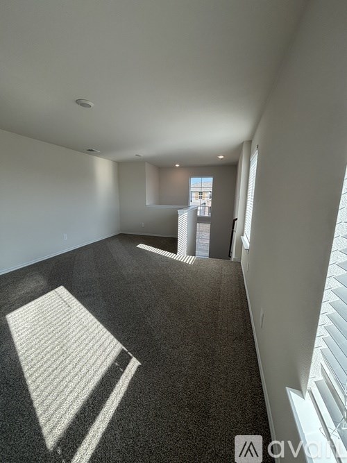 A long hallway with a carpeted floor and a window on the right side.