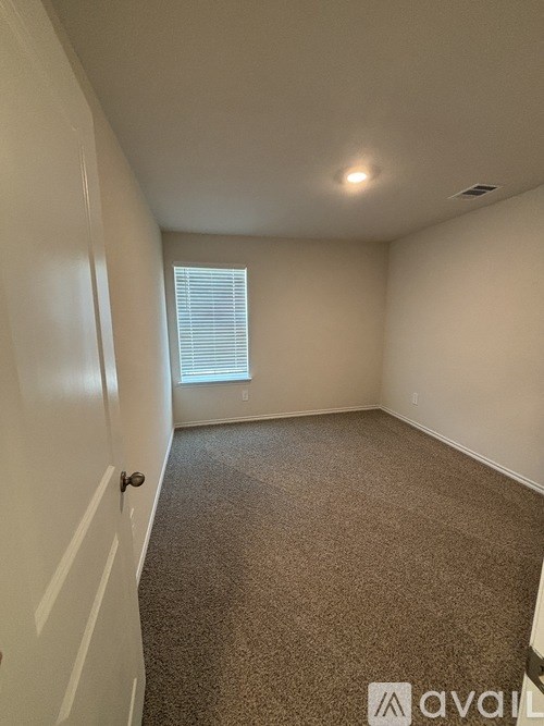 A carpeted room with a door and a window.