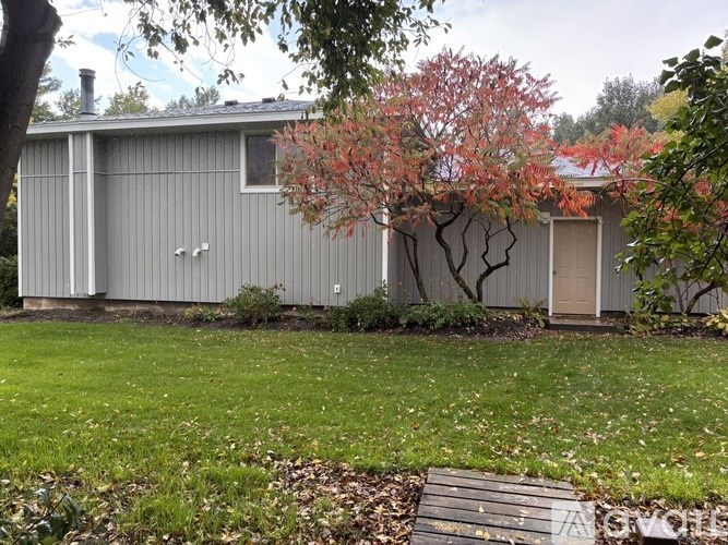 A grey house with a tree in front of it.
