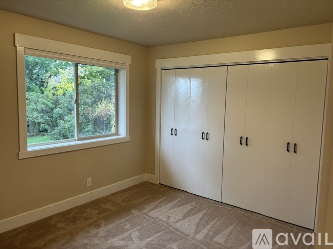 A room with a window and a set of white doors.
