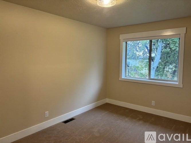 A room with a window and a carpeted floor.