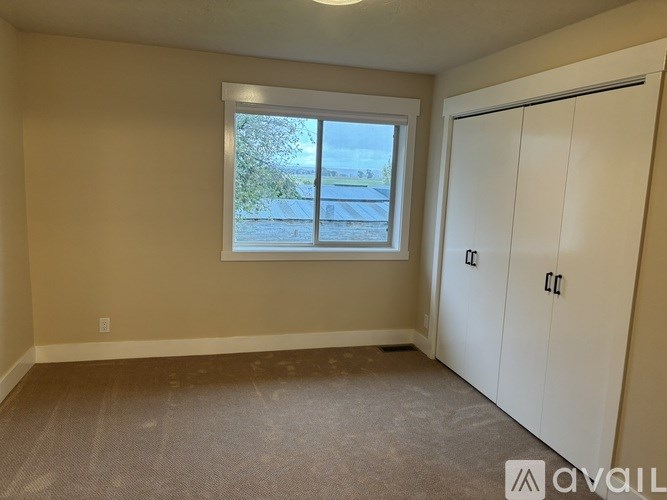 A room with a window and a white door is available for rent.