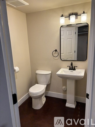 A bathroom with a toilet, sink and mirror.
