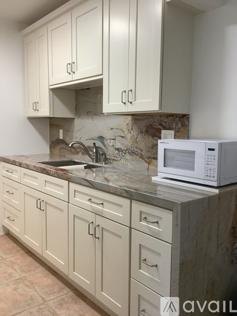 A kitchen with a marble countertop and white cabinets.