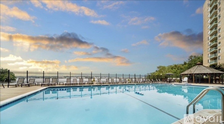 A large outdoor swimming pool with a sunset sky in the background.