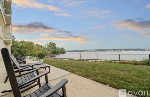 A balcony with two chairs and a table overlooking a body of water.