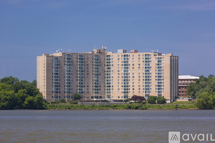 A large building with many windows sits by a body of water.