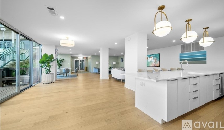 A spacious kitchen and living room with white cabinets and wooden floors.