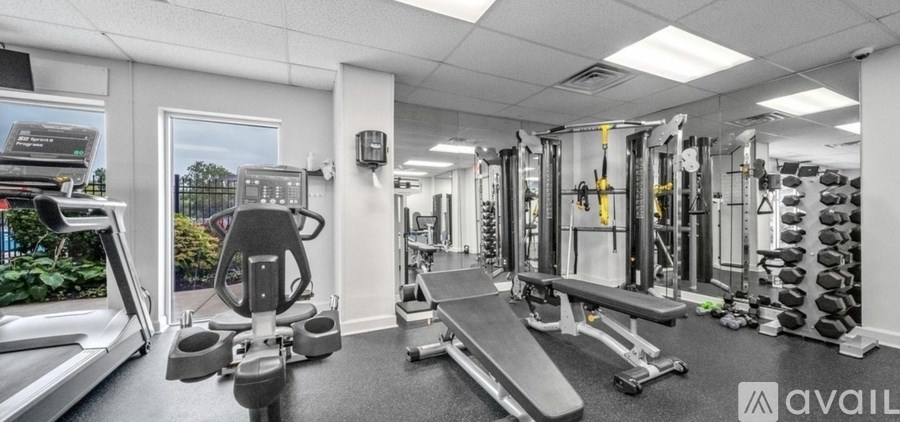 A gym with a variety of equipment including treadmills, weights, and benches.