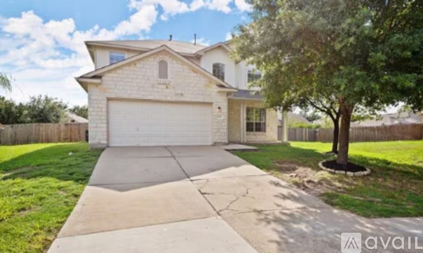 A house with a white garage door and a tree in front.