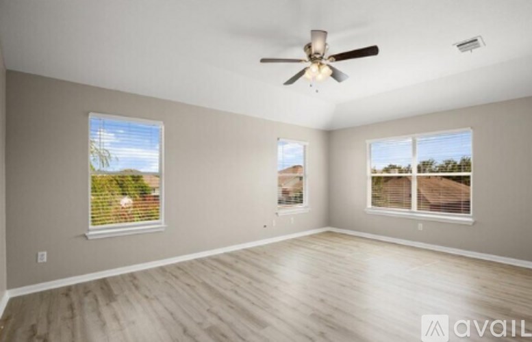 A spacious room with a ceiling fan and two windows.