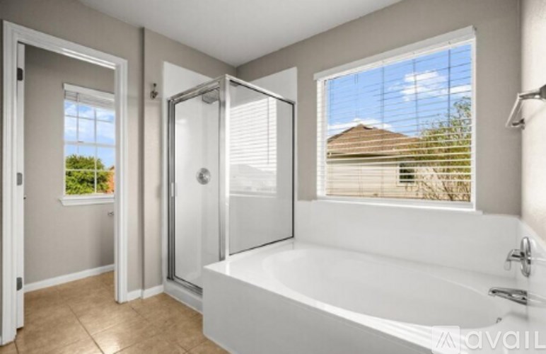 A bathroom with a large tub and a window overlooking a house.