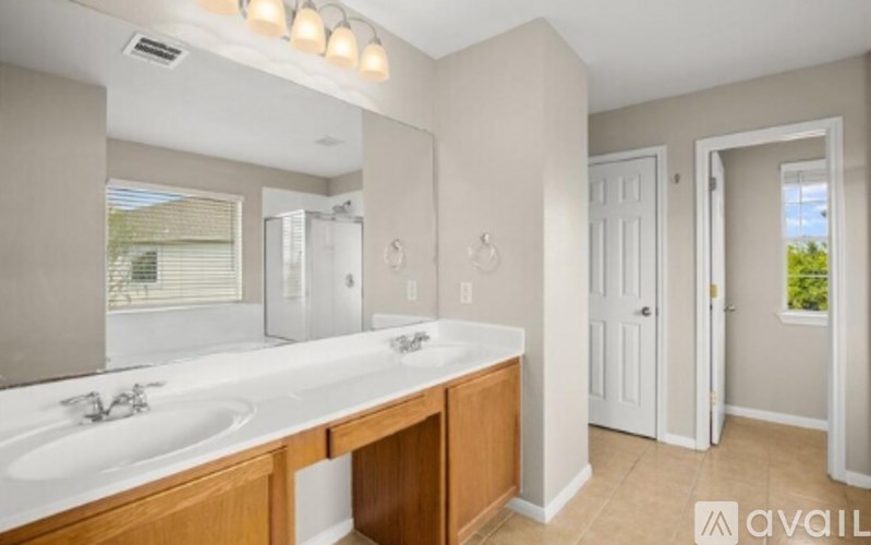A bathroom with a large mirror, a double sink vanity, and a door leading to a balcony.
