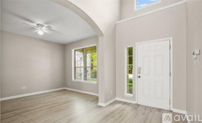 A room with a white door and a window with a view of trees.