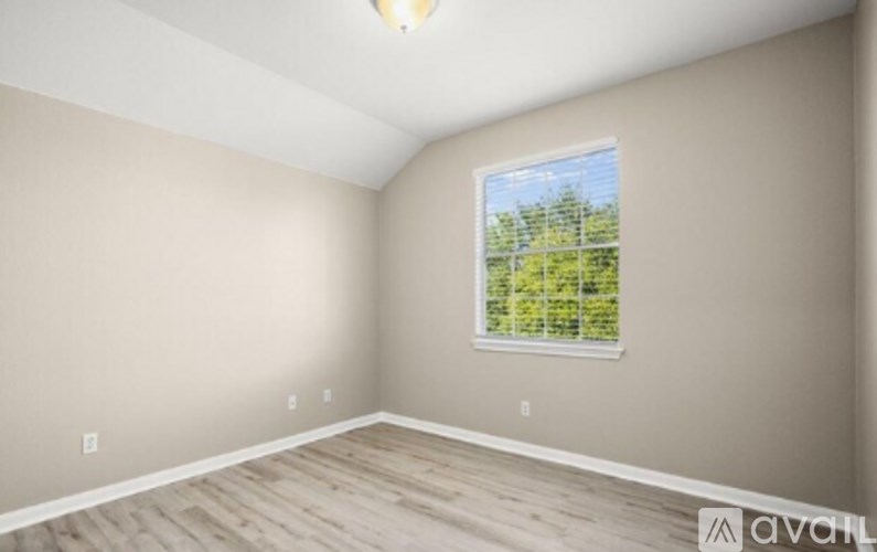 A room with a window and wooden flooring.